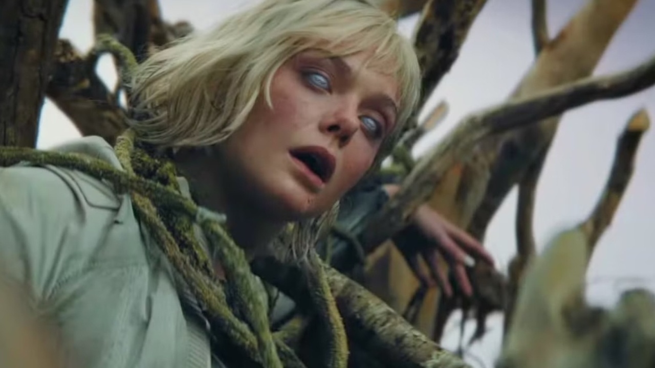 Οθόνη από το Predator Badlands που δείχνουν ένα ξανθό θηλυκό Android που κρέμεται σε μερικά αμπέλια, με τα μάτια του εντελώς λευκά.